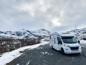 A motorhome driving through snow-covered mountains in Scotland.